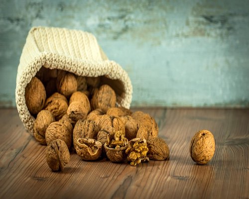 Assorted raw almonds, walnuts and sunflower seeds scattered on a plain wooden table