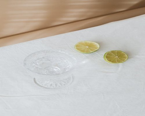 A clear glass of pure water next to a fresh tropical lime and writing tools on a bright table